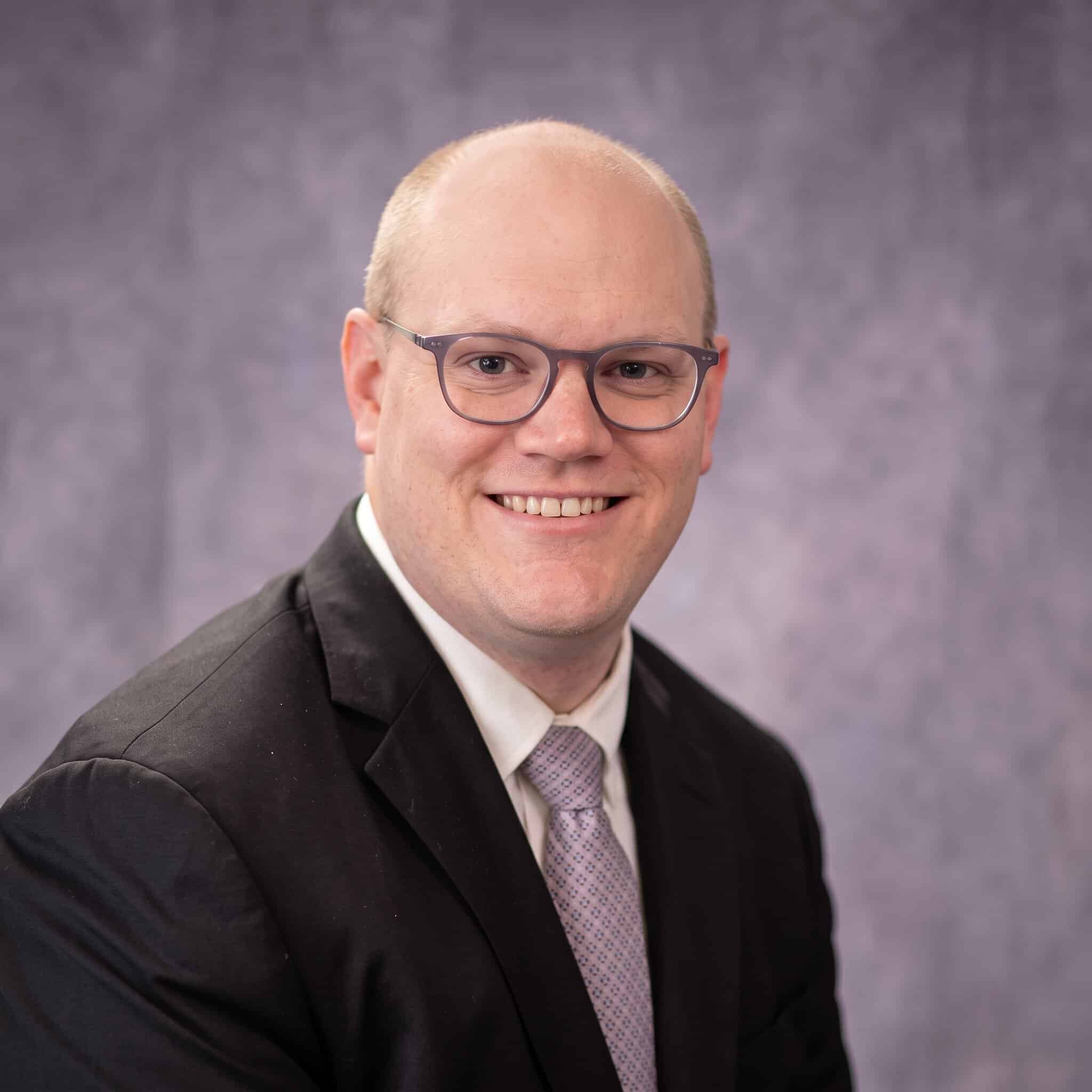 Smiling man in suit and glasses at the 2026 ESP Workshop.