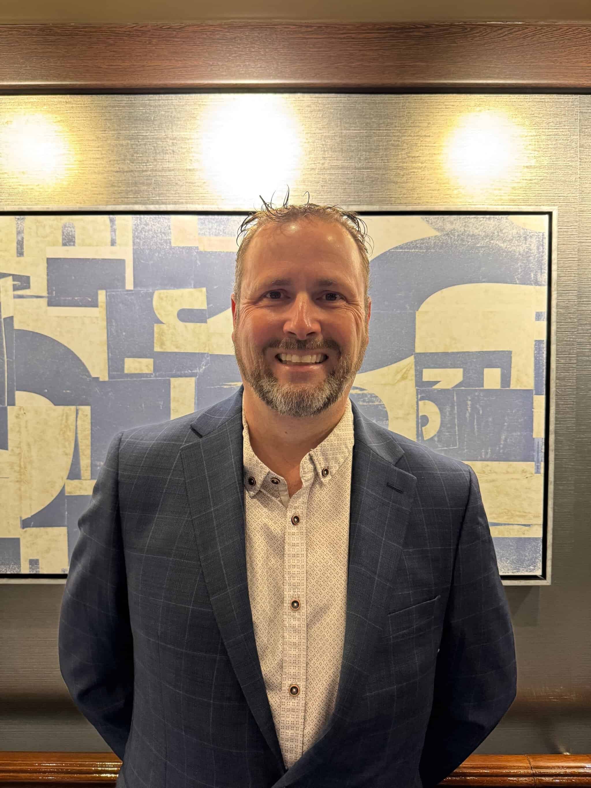Smiling man in suit at 2026 ESP Workshop event in front of artwork.